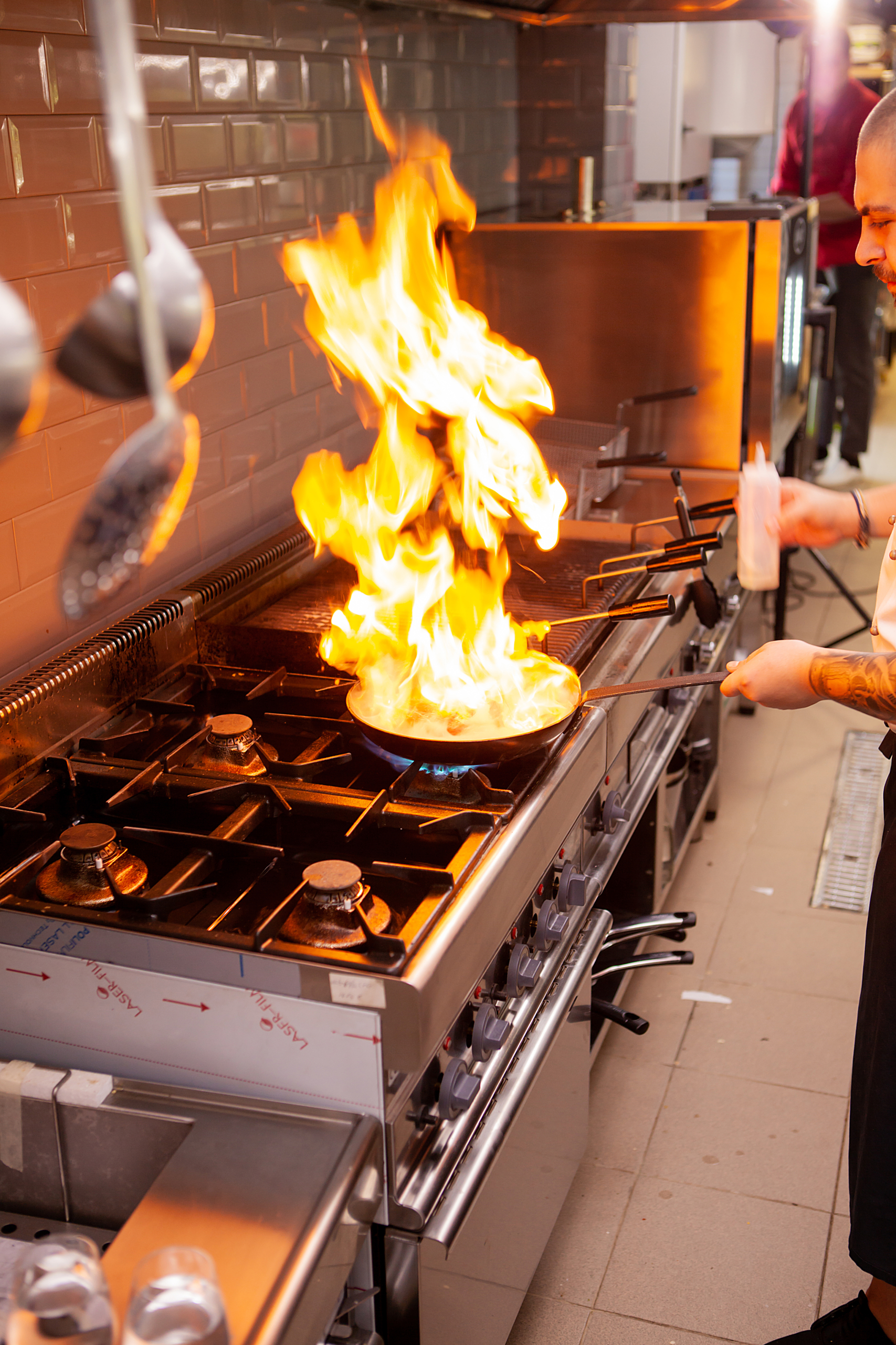 The chef prepares the dish on the stove with an open fire in the kitchen of the restaurant.